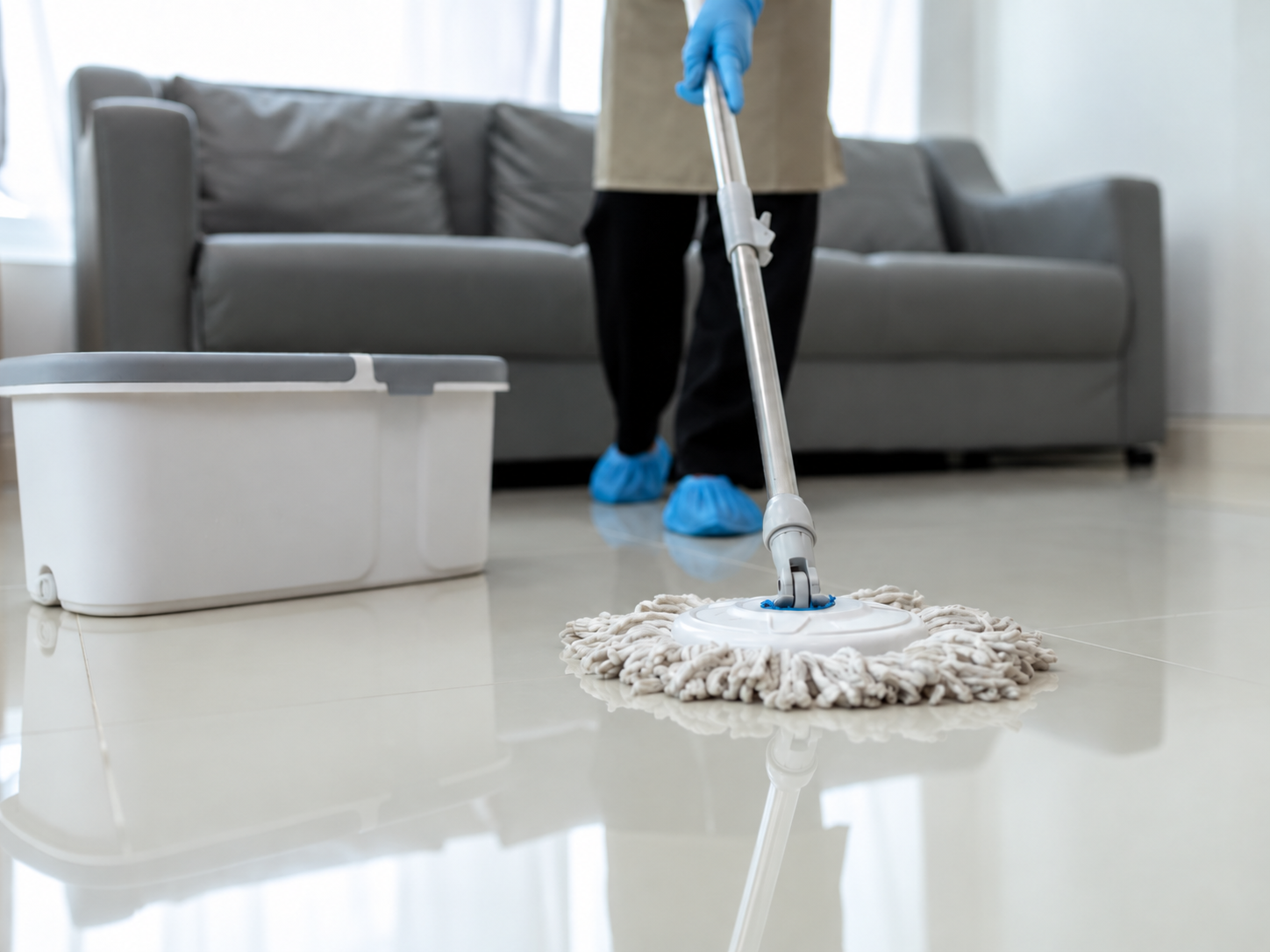 Cleaner mopping a living room floor beside a sofa